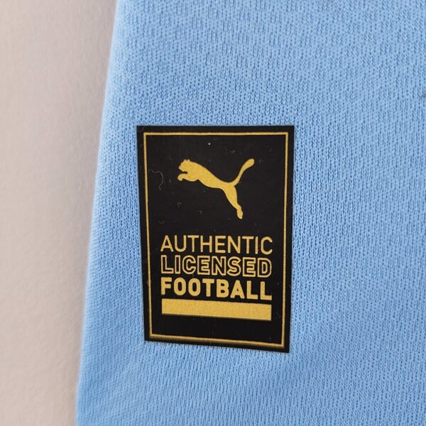 Camiseta Manchester City 2023/24 Local - detalle escudo y sponsor